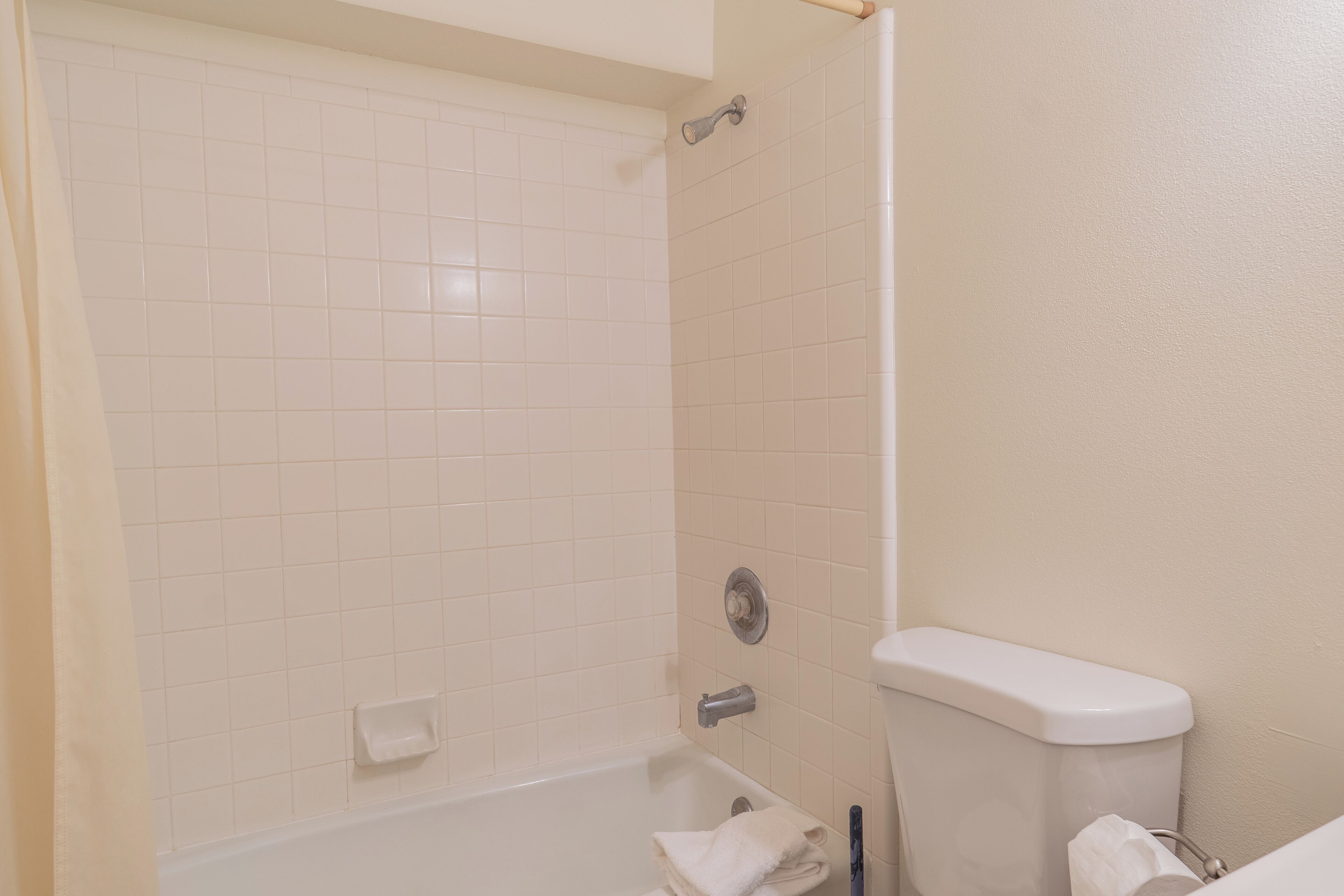 Een badkamer met witte tegels, een bad, een toilet en een handdoekrek.