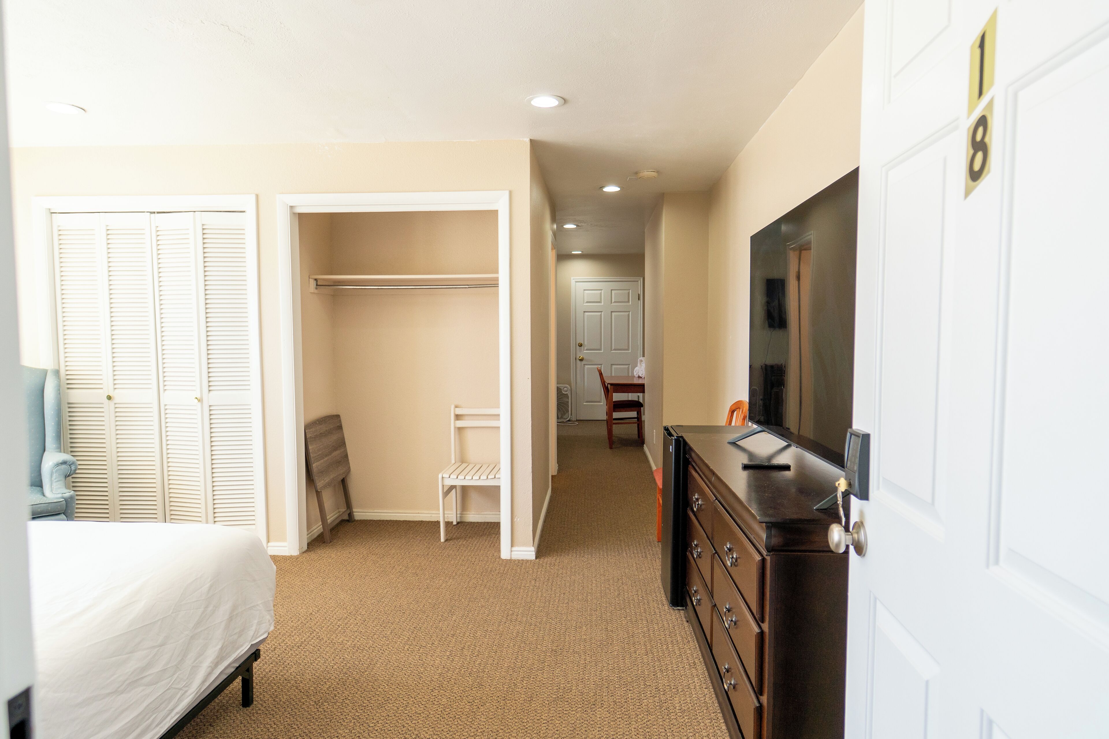 A bedroom with a bed, a dresser, a closet, and a desk with a chair.
