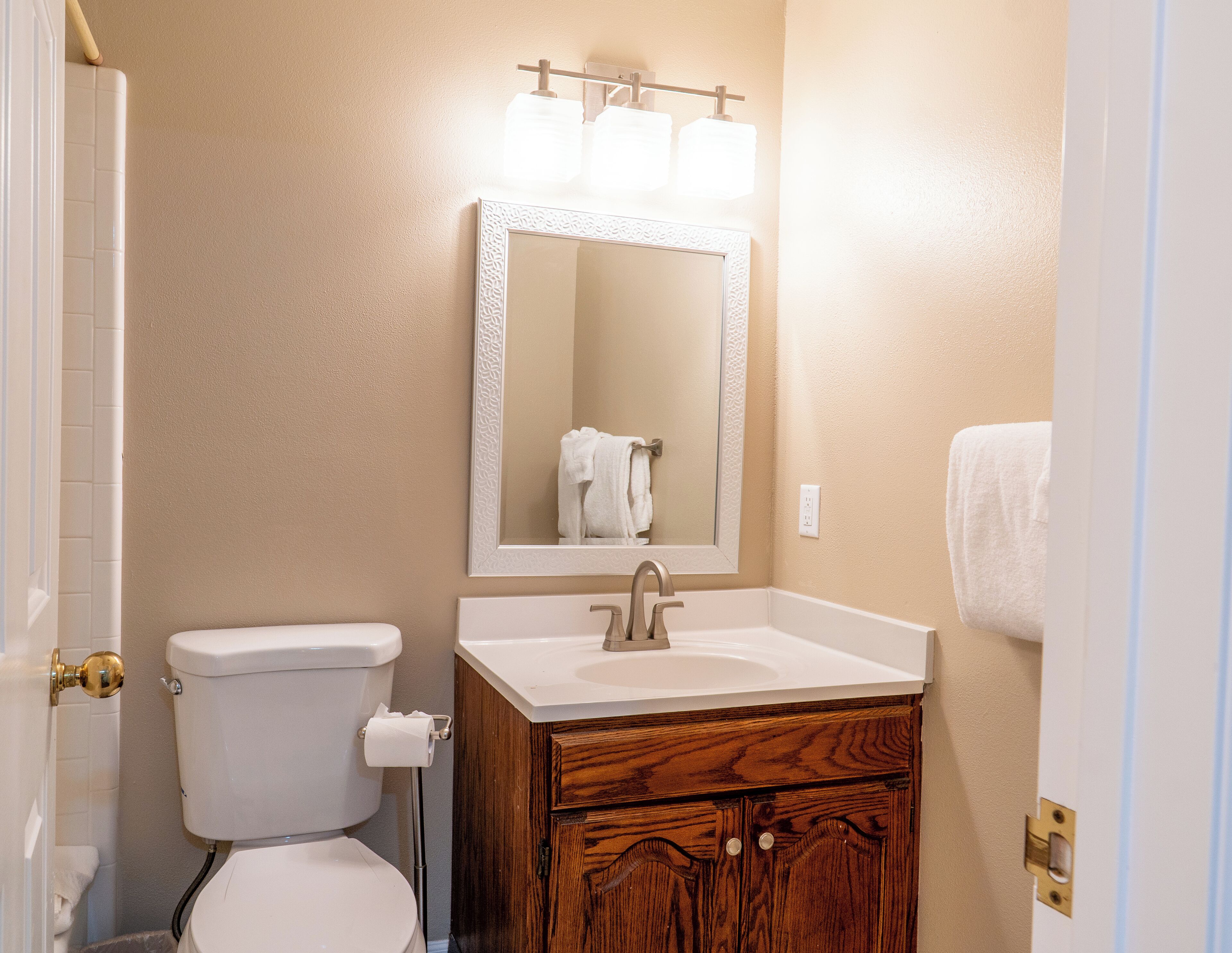 A bathroom with a toilet, sink, and mirror.