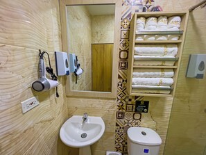 A bathroom with a sink, a mirror, a towel rack with towels, and a toilet. - AMGES (Tumaco)