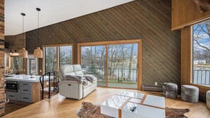 Ein modernes Wohnzimmer mit großem Fenster, einer Couch, einem Couchtisch und einem Kamin.