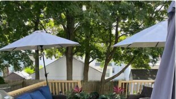 Un área de patio al aire libre con una parrilla, un sofá azul y dos sombrillas.