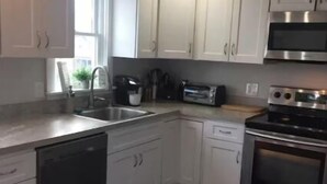 Una cocina moderna con gabinetes blancos, electrodomésticos de acero inoxidable, lavavajillas y horno empotrado.