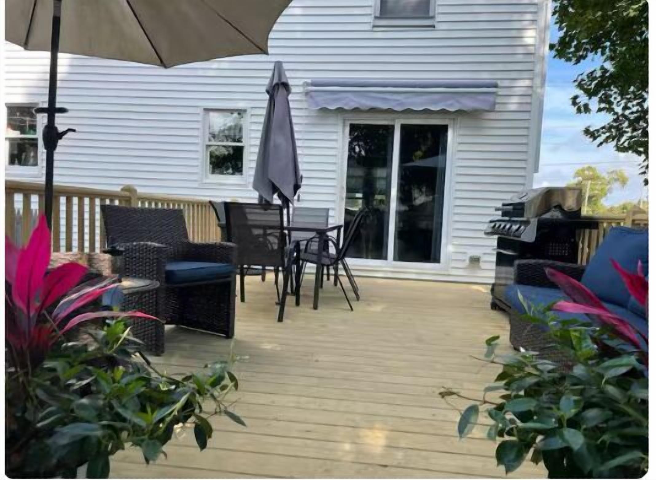 Une terrasse couverte, aménagée avec du mobilier d’extérieur, un barbecue et des plantes en pot.