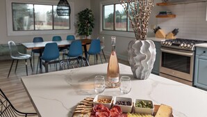 Una cocina moderna con encimera de mármol, una botella de vino, quesos y embutidos variados.