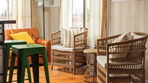 Una habitación con muebles de mimbre, un sofá de cuero y taburetes verdes.