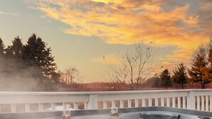 Un jacuzzi con vistas a árboles y al atardecer.