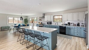 Una cocina moderna con una isla central, taburetes de bar y armarios azul claro.
