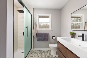 A modern bathroom with a shower, toilet, and sink.