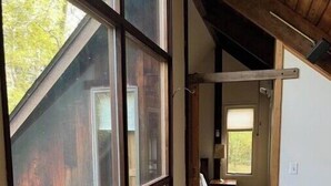 Una habitación amplia con ventanas grandes, suelo de madera y vistas al exterior.