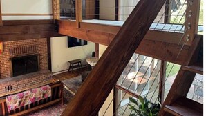 Un interior de madera con varios niveles, chimenea, comedor y amplias ventanas.