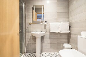 A modern bathroom with a glass shower enclosure, a pedestal sink, and a toilet. - Ewings Bar & Self-Catering Accommodation (Carlow)