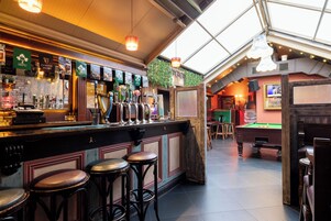 A bar area with multiple stools, a pool table, and a variety of beer taps.