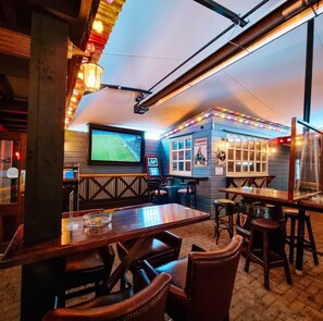 A cozy bar with wooden furniture, a large TV screen, and Guinness branding. - Ewings Bar & Self-Catering Accommodation (Carlow)
