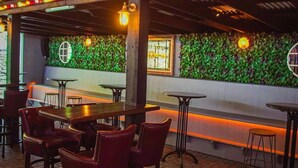 A restaurant with a green wall, wooden tables, and red chairs. - Ewings Bar & Self-Catering Accommodation (Carlow)
