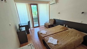 Een hotelkamer met een bed, een bureau, een stoel en een schuifpui naar het balkon.