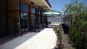Een buitenpatio met een overdekte zithoek, potplanten en uitzicht op de gevel.