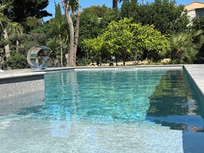 Relax by the serene pool surrounded by lush greenery and a decorative sculpture.
