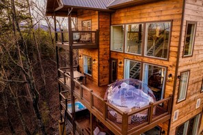 A multi-level wooden cabin with balconies, large windows, and a glass dome structure. - Stargazing Pool Golf Murals (Sevierville)