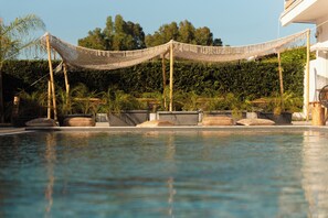 Ein Pool mit Netzverdeck, umgeben von Palmen und Pflanzgefäßen.
