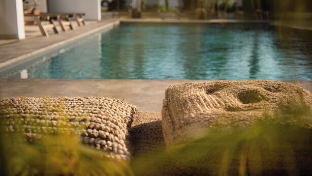 Un área de piscina con vista despejada al agua, una silla de descanso y una zona de estar con textura.