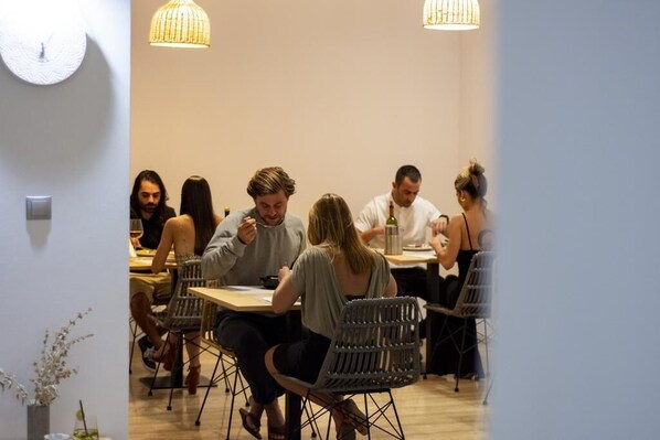 A restaurant with a modern interior, featuring wicker chairs and a wooden table.