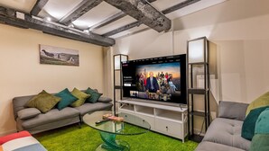 A modern living room with exposed beams, a flat-screen TV, a glass coffee table, and a green carpet. - Spacious home, sleeps 9 - walker & cyclist retreat -Pass the Keys (Shropshire)