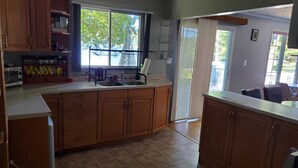 Una cocina con armarios de madera, microondas y ventana con vista a árboles.