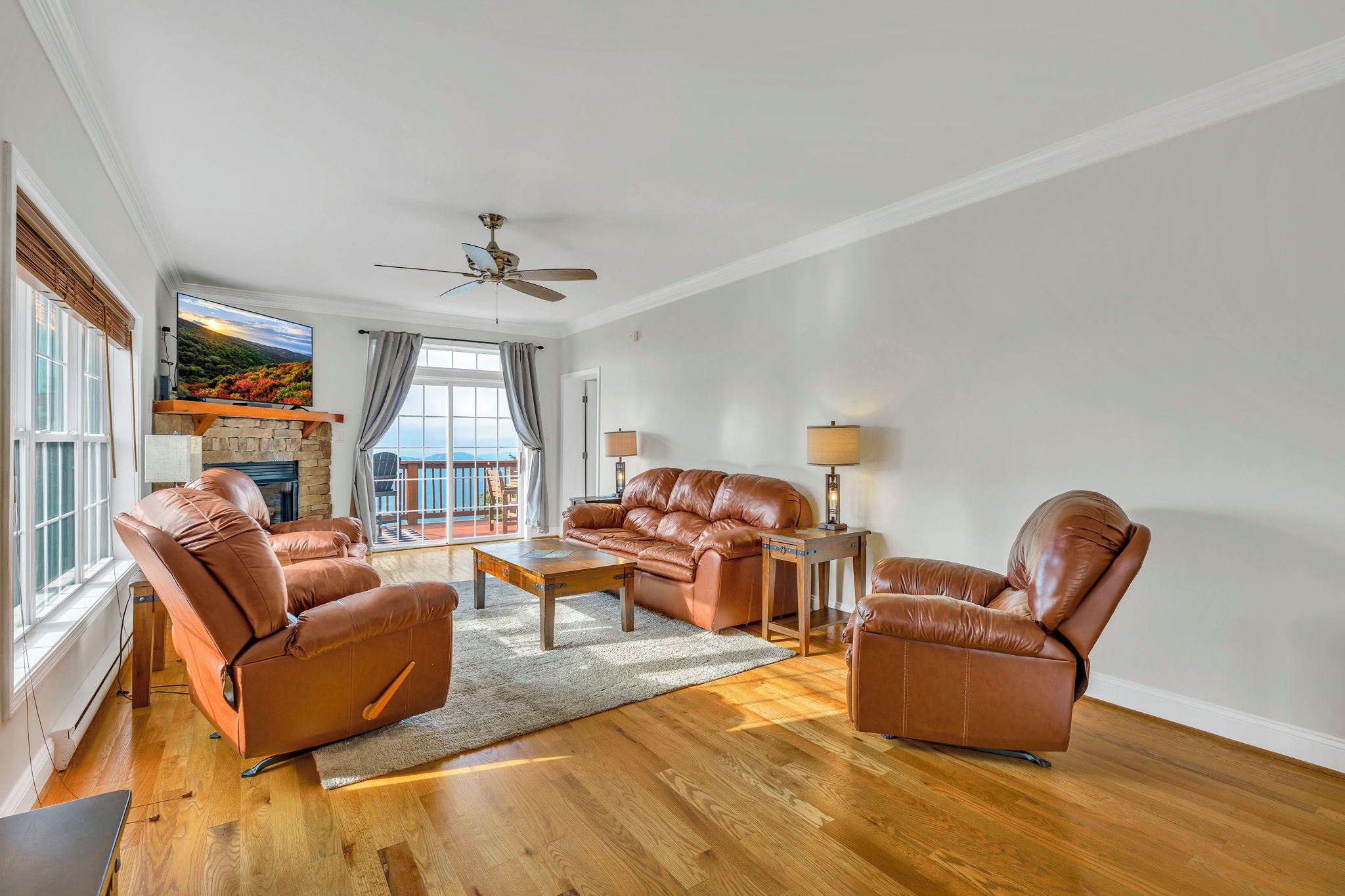 Amplia sala de estar con muebles de cuero, chimenea y un ventanal con vistas.
