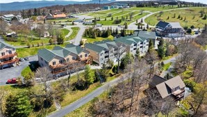 Un quartier résidentiel comprenant plusieurs maisons, une rue principale et un grand bâtiment en arrière-plan.