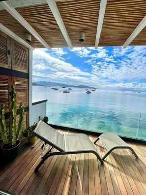 A wooden deck with two lounge chairs overlooking a calm sea with boats, under a clear sky. - Surfer Caravan Gastro Pub and Suites (Bodrum)