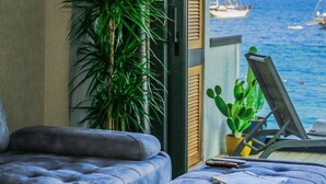 Ein Balkon mit Meerblick, ausgestattet mit einer Couch, einem Hocker und einer Topfpflanze.