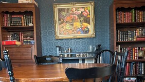 Un comedor con una mesa y sillas de madera, rodeado de estanterías llenas de libros.