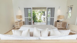 A bedroom with a bed, two bedside tables, a window, and a balcony with a view of greenery. - Exclusive one bedroom apartment, a few steps from the Caribbean Sea (Speightstown)