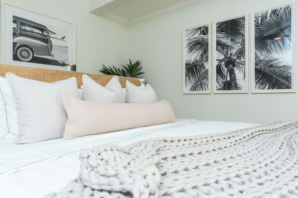 Un dormitorio con cama, almohadas, colcha y decoración en la pared.