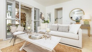 A modern living room with a white sofa, a coffee table, and a wicker chair. - Exclusive one bedroom apartment, a few steps from the Caribbean Sea (Speightstown)