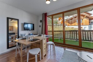A modern kitchen with a dining area, a TV, and a large sliding glass door leading to a deck. - 200m from ski slopes, 3rd floor, swimming pool, balcony, tv, ski locker, 24m², Les Orres (Les Orres)
