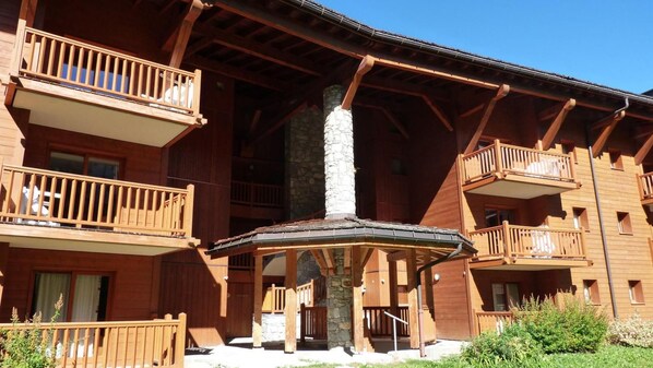 A wooden multi-story building with balconies and a central stone pillar.