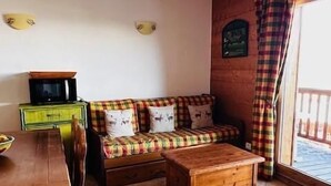 Una sala acogedora con un sofá, una mesa de centro de madera y una mesa de comedor.