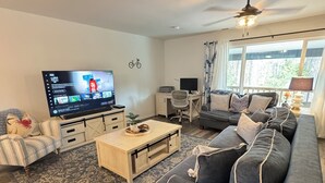 A living room with a sofa, a coffee table, a TV, and a desk.