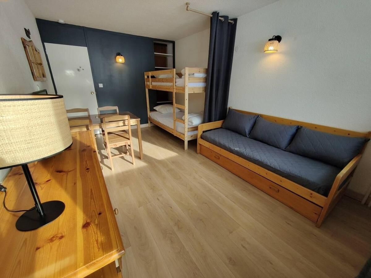 Et værelse med køjeseng, sofa, skrivebord med lampe og en stol.