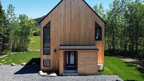 A modern wooden cabin with a steep gable roof, large windows, and a gravel driveway. - Hôtel à la maison - La Villa Foresta (Coaticook)