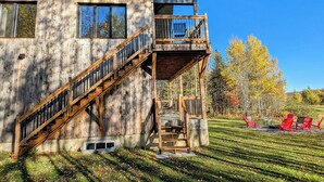A rustic wooden house with a balcony, a staircase, and a well-maintained lawn. - Hôtel à la maison - La Villa Foresta (Coaticook)