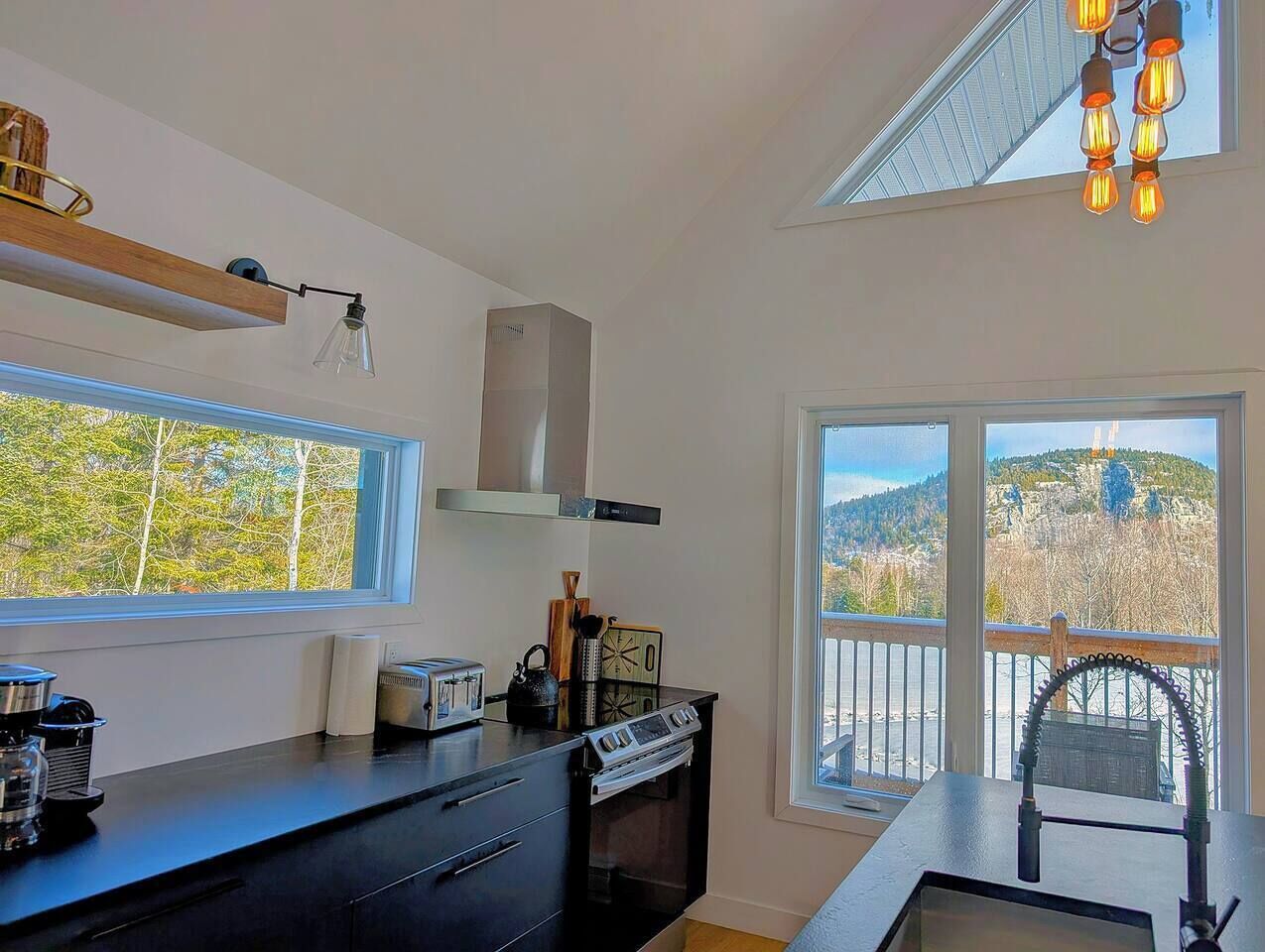 Una cocina moderna con un amplio ventanal, horno empotrado y vistas a un paisaje montañoso.