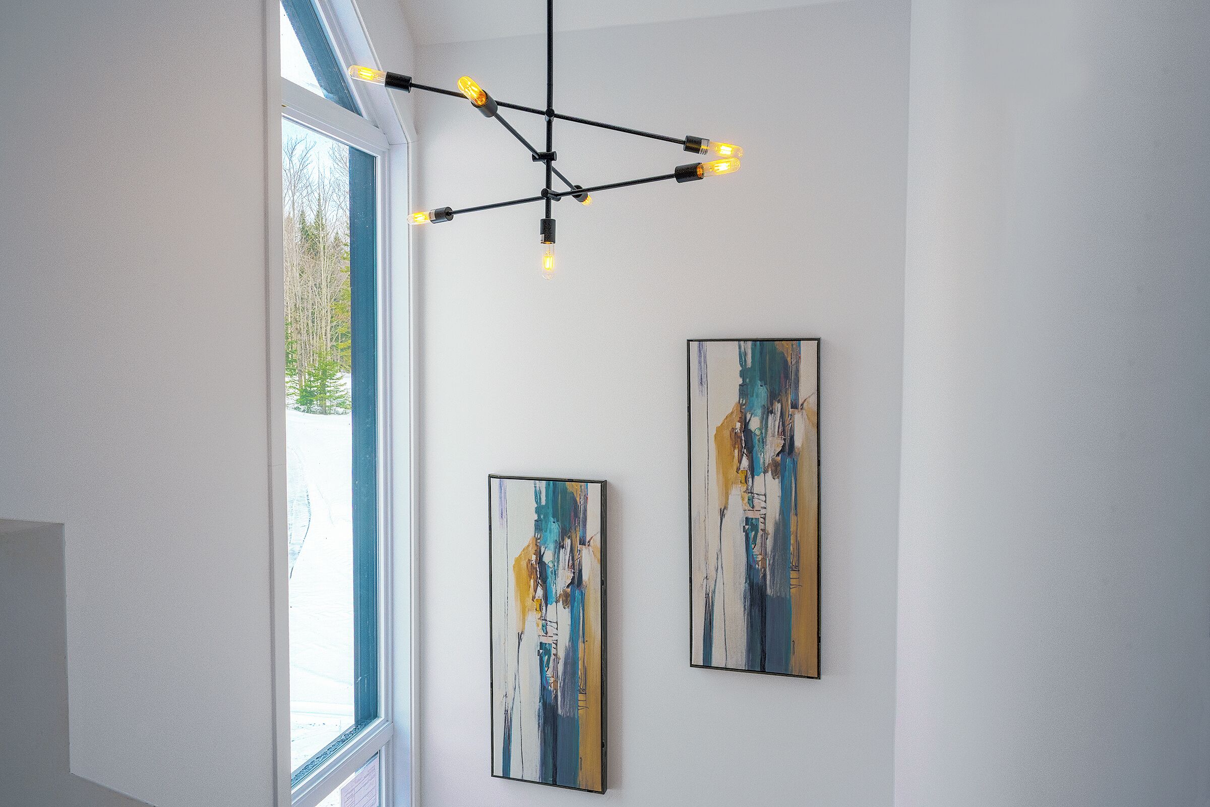 Un interior moderno con una lámpara de techo y cuadros abstractos en la pared.