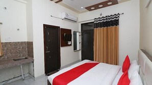 A hotel room with a bed, a TV, a sink, and a mirror. - Vrinda Residency (Vrindavan)
