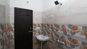A bathroom with a black door, a white sink, and floral patterned tiles. - Vrinda Residency (Vrindavan)