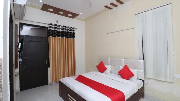 A hotel room with a bed, a door, and a window. - Vrinda Residency (Vrindavan)