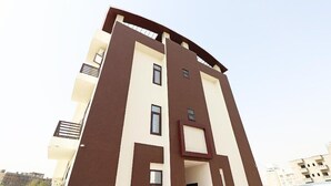 A multi-story building with a modern design, featuring a flat roof and a mix of beige and brown exterior colors. - Vrinda Residency (Vrindavan)