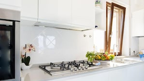 A modern kitchen with white cabinets, a stainless steel stove, and a bowl of fruit on the counter.